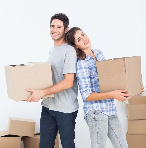 Husband and wife carrying boxes in their new house