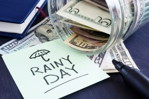 Rainy day fund savings. Jar with dollar bills.
