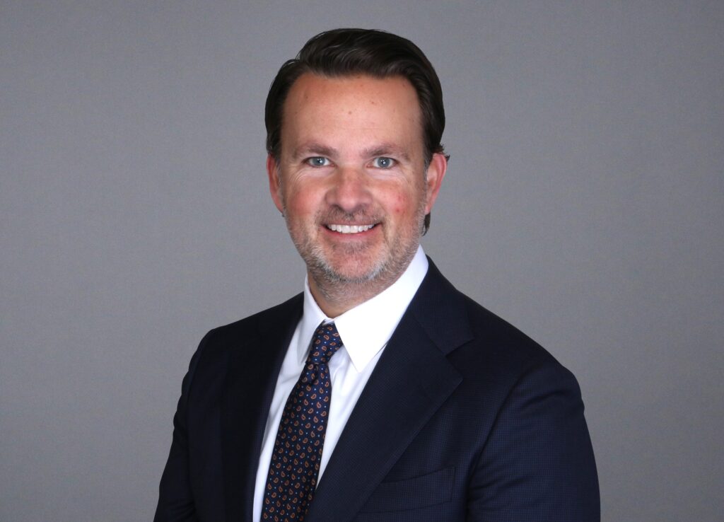 Portrait of a man smiling in a dark colored suit and tie