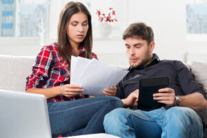 Man and Woman sitting on a couch looking at documents.