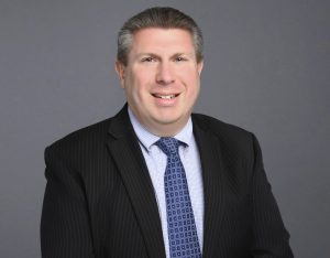 Portrait of Anthony Mattaliano smiling in suit and tie