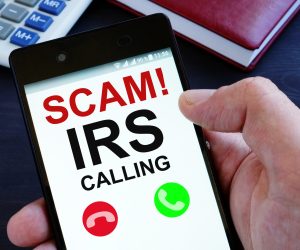 Phone with SCAM! IRS calling message shown.